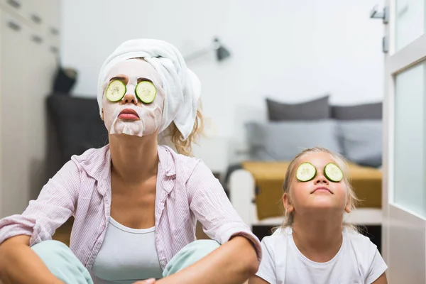 Anne ve kızı evde kozmetik maske takıyor.
