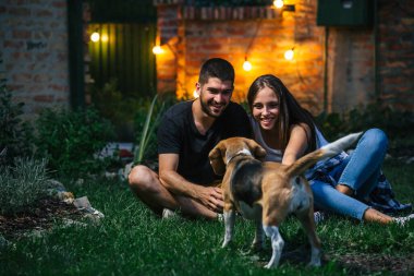 Arkadaşlar evlerinin arka bahçesinde köpekleriyle oynuyorlar. gece sahnesi