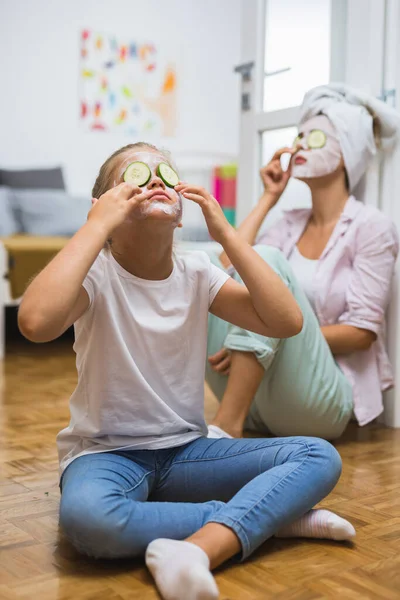 mother and daughter applying cosmetic face mask at home