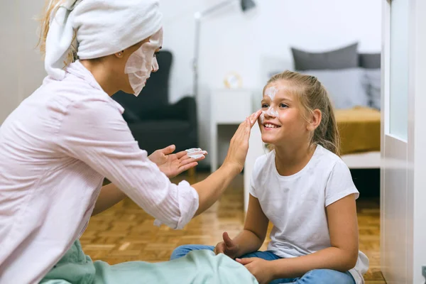 Anne ve kızı evde kozmetik maske takıyor.