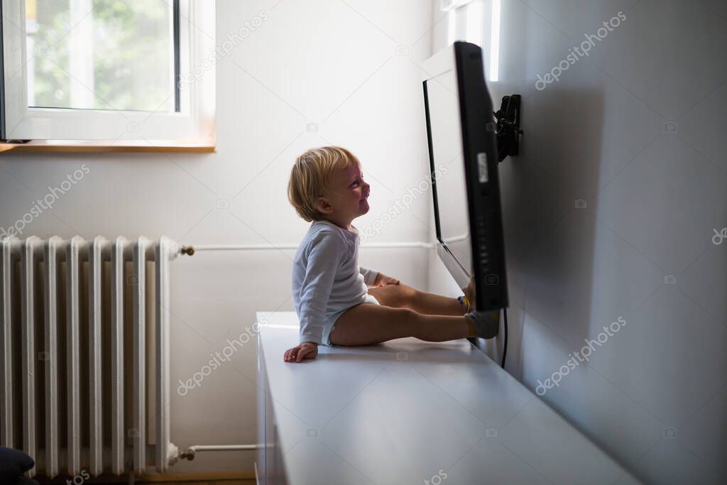 cute little boy watching television at his home