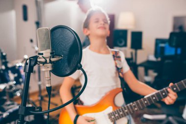 Stüdyo mikrofonunu kapat ve arka planda gitar çalan bulanık çocuk