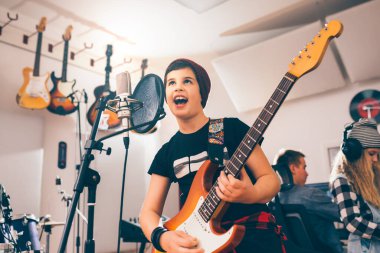 Çocuk müzik stüdyosunda gitar çalıyor.