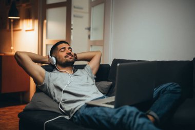 Adam evinde dinleniyor ve müzik dinliyor.