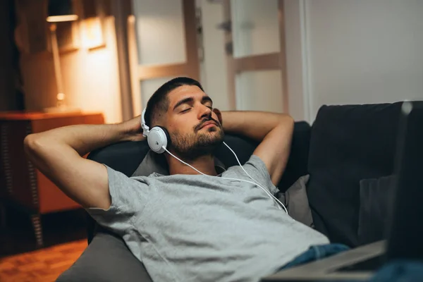Adam evinde dinleniyor ve müzik dinliyor.