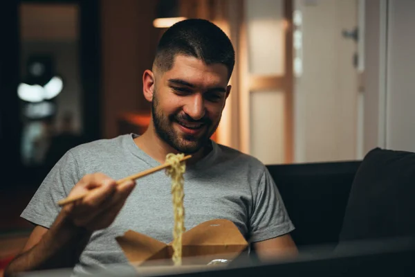 Mężczyzna Relaksujący Się Swoim Mieszkaniu Jedząc Chińskie Jedzenie Korzystając Laptopa — Zdjęcie stockowe