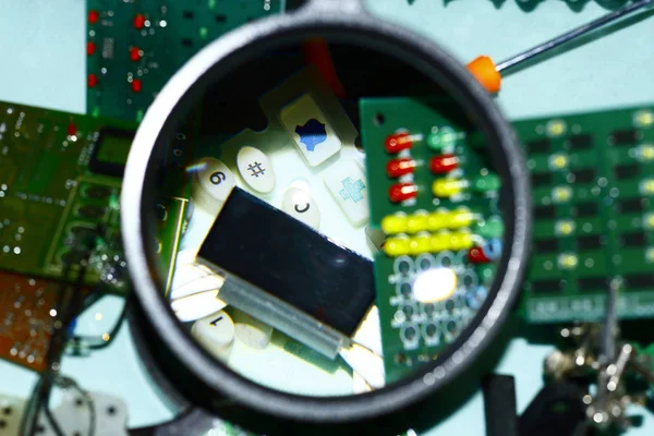 Elektronik bileşenleri devre kartlarına Büyüteç ön planda ile basılmış.