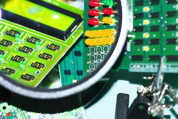 Elektronik bileşenleri devre kartlarına Büyüteç ön planda ile basılmış.
