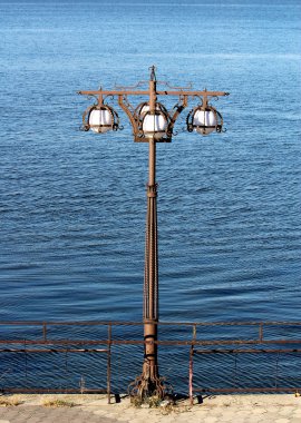 Arka plan mavi nehir ve köprü ile bir elektrik direği ile metal heykel beyaz plofony 