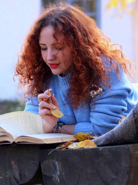 Kadın sonbahar parkta. bir bankta bir peçe ile yalan ve bir kitap okuma. Sonbahar arka plan