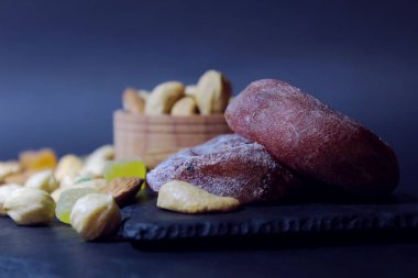 Görünüm doğrudan şekerlenmiş meyve, fındık ve Kuru hurma. Karanlık bir arka plan üzerinde bir tabakta yemiş/kuru meyveler vardır. etkisi bulanıklık