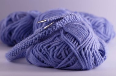 Görüş iplik, örgü iğneleri ve örme döngüler yalan masada örgü mavi topları. Örgü doku. Etkisi bulanıklık.