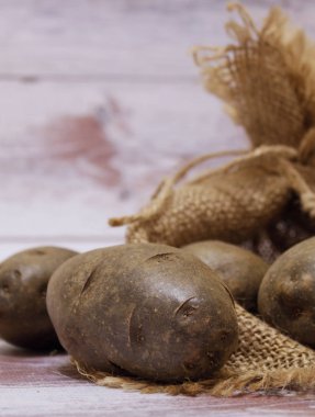 Patatesin yatay görünüm için patates çanta yakınındaki hafif bir arka plan üzerinde
