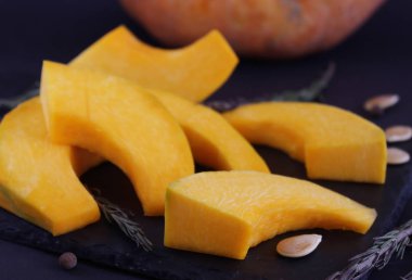 Kabak dilim üzerinde yakın çekim, hangi karanlık bir tabak üzerinde yatıyor. Etkisi bulanıklık. Ev yapımı ve sağlıklı yemekler pişirmek için malzemeler. Sağlıklı beslenme kavramı