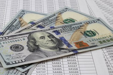 Hem finansal hem de iş kavramları için abd parası, sayı tablolarının olduğu bir masada yatıyor. Bankacılık, yatırımlar, mevduat, tasarruf.