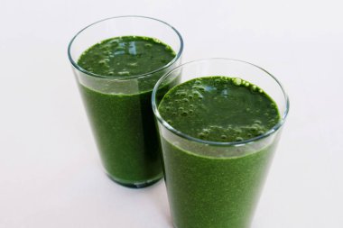 Beyaz arka planda lahana yaprakları, muz, Hindistan cevizi sütü, Spirulina ve Keten tohumları ile taze yeşil smoothie. Sağlıklı gıda