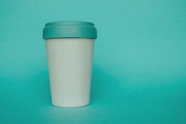 Açık mavi arka planda kahve almak için yeniden kullanılabilir plastik çevre dostu bambu kupası.