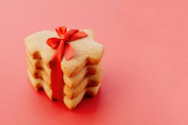 Güzel kırmızı kurdeleyle bağlanmış noel ağacı şeklinde kurabiye yığını.