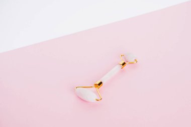Pembe kuvarstan yapılmış yeşil taş silindir. Pembe arka planda lenfatik drenaj yüz masajı için doğal bir alet. Uzayı kopyala, kapat. Güzellik ve vücut bakımı.