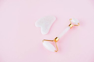 Pembe kuvarstan yapılmış yeşil taş silindir. Pembe arka planda lenfatik drenaj yüz masajı için doğal bir alet. Uzayı kopyala, kapat. Güzellik ve vücut bakımı.