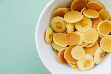 Nane yeşili arka planda bir kasede taze pişmiş gözleme gevreği, yakın plan, üst manzara. Uzayı kopyala Mini gözleme. Çocuklar için yemek. Kahvaltı fikirleri..