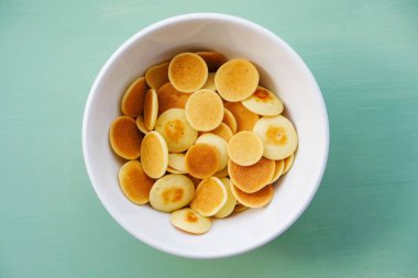 Nane yeşili arka planda bir kasede taze pişmiş gözleme gevreği, yakın plan, üst manzara. Uzayı kopyala Mini gözleme. Çocuklar için yemek. Kahvaltı fikirleri..