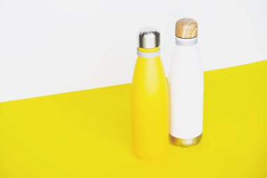 Yeniden kullanılabilir, çevre dostu paslanmaz, sarı arka planda çelik termo şişeler. Uzayı kopyala Sıfır atık, plastiksiz, sürdürülebilir yaşam tarzı konsepti.