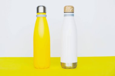 Yeniden kullanılabilir, çevre dostu paslanmaz, sarı arka planda çelik termo şişeler. Uzayı kopyala Sıfır atık, plastiksiz, sürdürülebilir yaşam tarzı konsepti.