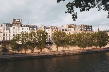 Gün batımında Seine nehrinin yanında güzel binaları olan Paris şehri manzarası.