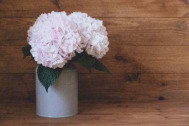 Güzel, taze pastel renkli ortanca çiçeklerinden oluşan bir buket vazo, ahşap kırsal arka planda çiçek açıyor. Boşluğu kopyala.