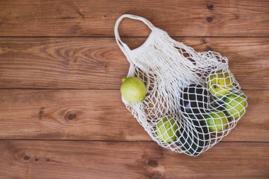 Üzerinde limon ve ahşap kırsal arka planda avokado bulunan yeniden kullanılabilir çevre dostu pamuk ağ torbası. Uzayı kopyala, üst görünüm. Sıfır atık, plastik yok. Kendi alışveriş çantası konseptini getir. Çiftçi pazarı.