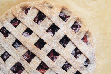 Beyaz arka planda taze böğürtlenlerle dolu ev yapımı vişneli turta ve üzerine pudra şekeri, yakın plan. Örgü turta kabuğu.