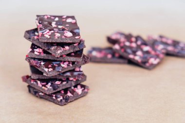 Kırmızı meyveli siyah çikolata parçaları kağıt kaplama arka planda, yakın plan. Boşluğu kopyala.