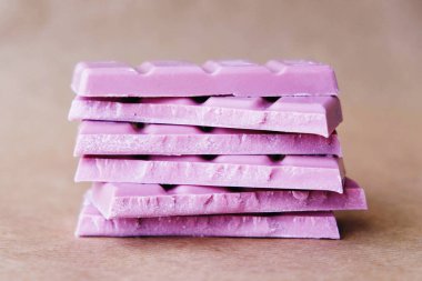 Açık kahverengi arka planda pembe çikolata yığını, kapatın..