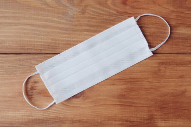 Ahşap arka planda beyaz koruyucu maskeler, üst manzara. Kişisel hijyen, sağlık ve Coronavirus Covid-19 önleme.