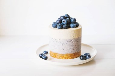 Beyaz arka planda vegan vanilyalı yabanmersinli cheesecake.