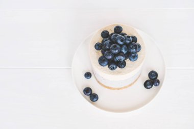 Beyaz arka planda vegan vanilyalı yabanmersinli cheesecake.
