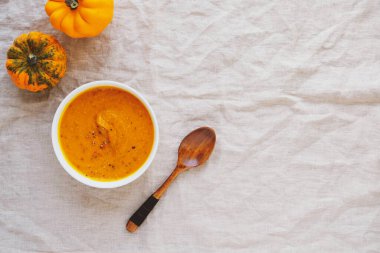 Beyaz masa örtüsünde bir kasede sıcak kabak çorbası..