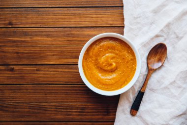 Tahta arka planda bir kasede sıcak kabak çorbası.