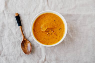 Beyaz arka planda bir kasede sıcak baharatlı balkabağı çorbası, üst manzara, düz yatak. Ev yapımı sonbahar yemekleri. Popüler Şükran Günü yemeği..