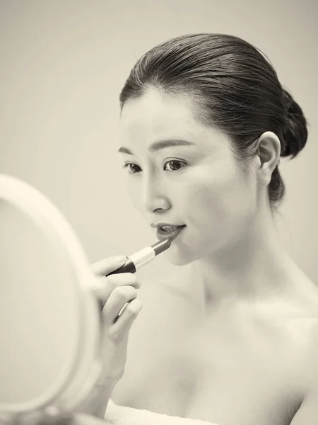 美丽的年轻的亚洲妇女在镜子中涂抹口红 而在嘴唇 复古风格的唇膏 — 图库照片