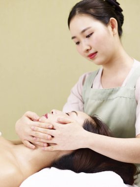 Genç Asyalı masör kadın spa salonda yüz masaj performans