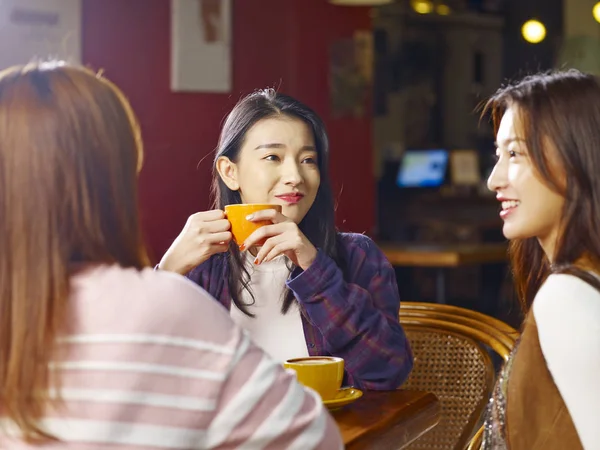 三愉快的美丽的年轻亚洲妇女坐在桌边聊天在咖啡馆或茶馆里谈话 — 图库照片