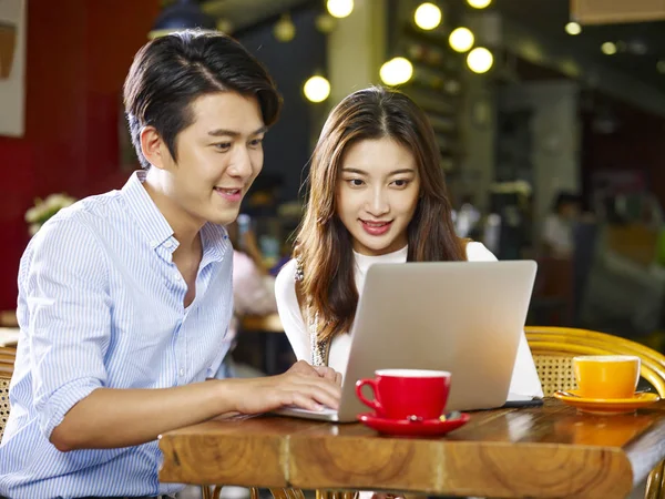 mutlu Genç Asyalı Çift kafede dizüstü bilgisayarla birlikte oturan.
