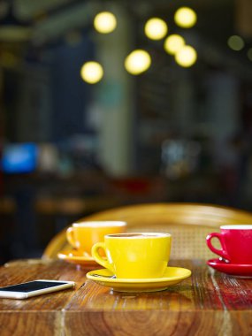 Üç fincan kapuçino ve bir cep telefonu bir kafede masada