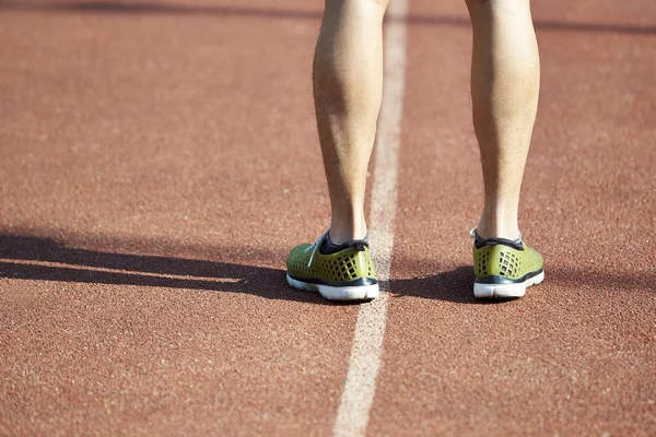 close-up of legs of a male athlete standing on track.