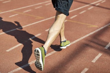 bacak ve yolda çalışan bir erkek atlet gölgesi.