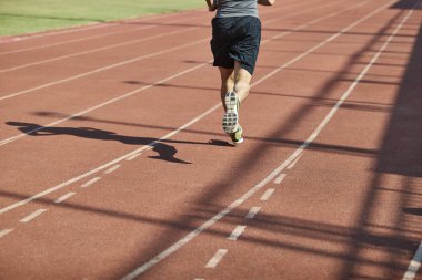 bacak ve yolda çalışan bir erkek atlet gölgesi.