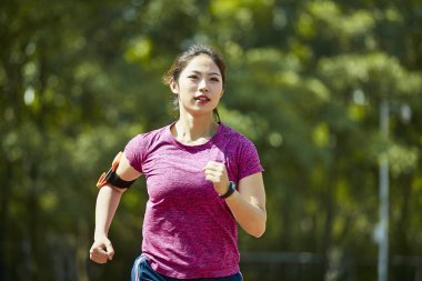 Genç Asyalı kadın atlet açık havada yolda eğitim çalışan.