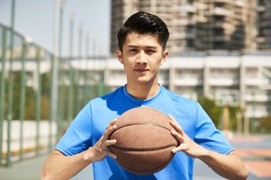 kameraya bakarak bir basketbol sahip Genç Asyalı erkek oyuncu.